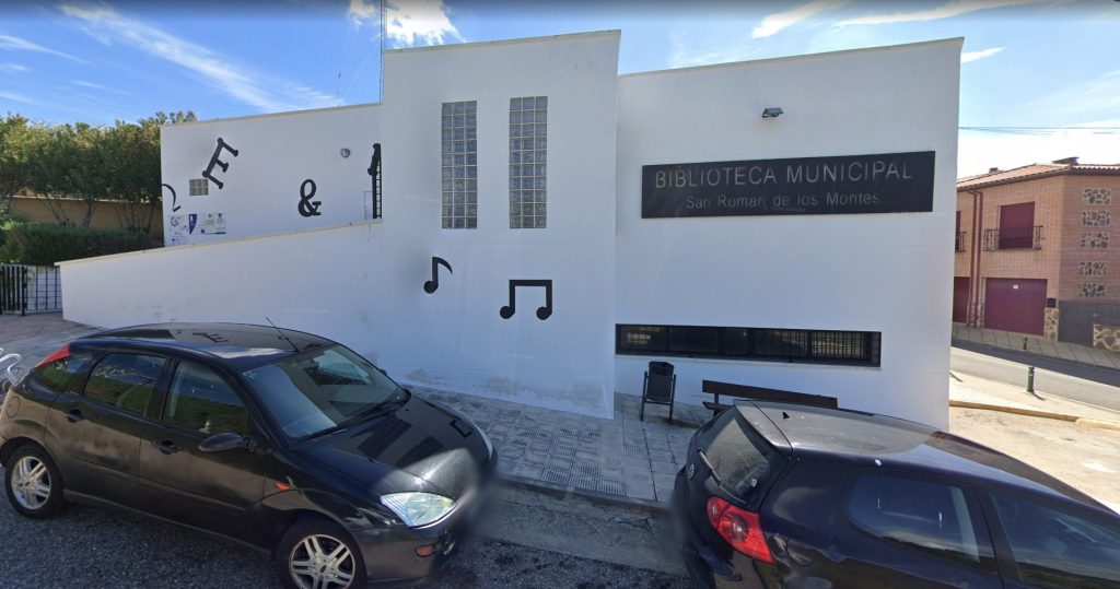 Fachada blanca de la Biblioteca Municipal de San Román de los Montes, con su rótulo y notas musicales decorativas