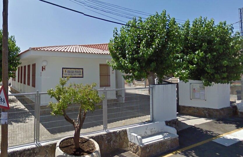Entrada del colegio público Nuestra Señora del Buen Camino: edificio blanco de tejado rojo, valla y árboles junto a la puerta