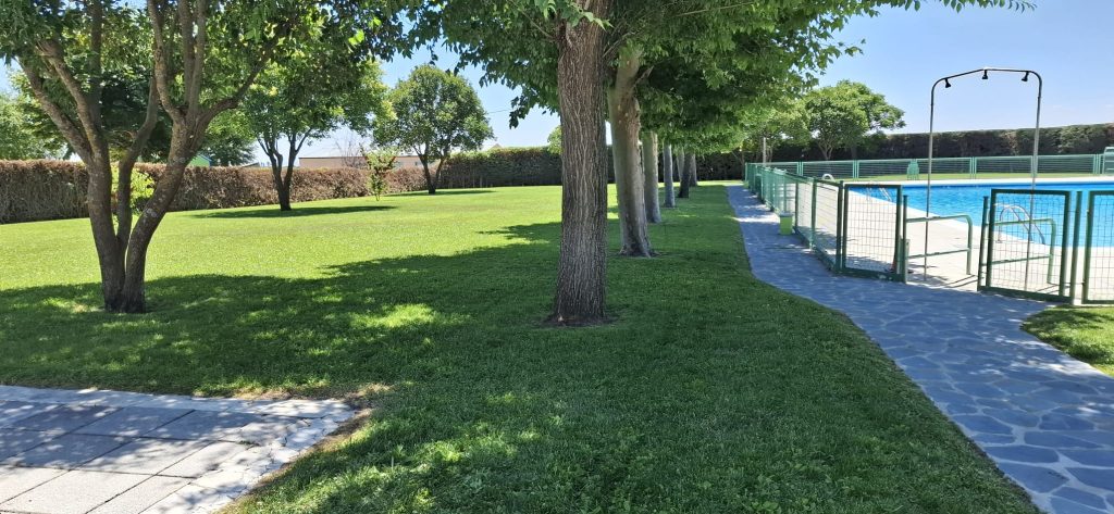 Paseo de piedra junto al césped y la valla de la piscina municipal