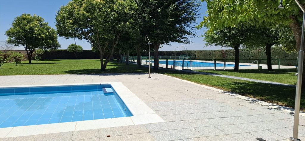 Vaso infantil de la piscina municipal con el césped y el vaso grande al fondo