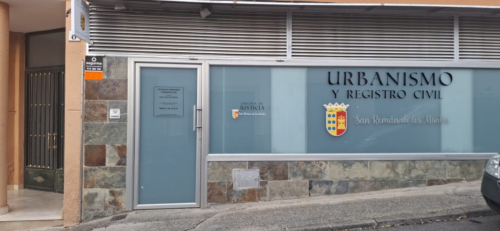 Fachada de la oficina de Urbanismo y Registro Civil, con cristalera azul, rótulo y escudo del Ayuntamiento